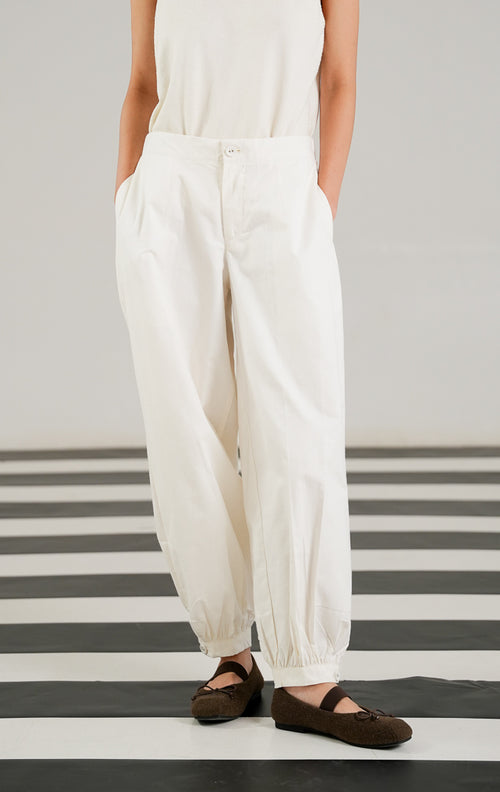 Celana panjang katun wanita Veilon Pants warna putih (White) dengan detail kancing di ujung kaki, lipit depan (pleats), dan ban pinggang karet belakang yang nyaman dari This Is April.