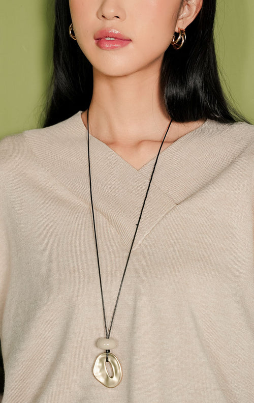 Sweater rajut wanita Venna Sweater lengan panjang warna beige polos, menampilkan detail kerah V-neck menyilang di bagian dada dengan aksen rajutan rib lebar yang khas, serta ujung lengan dan bawah beraksen rib.