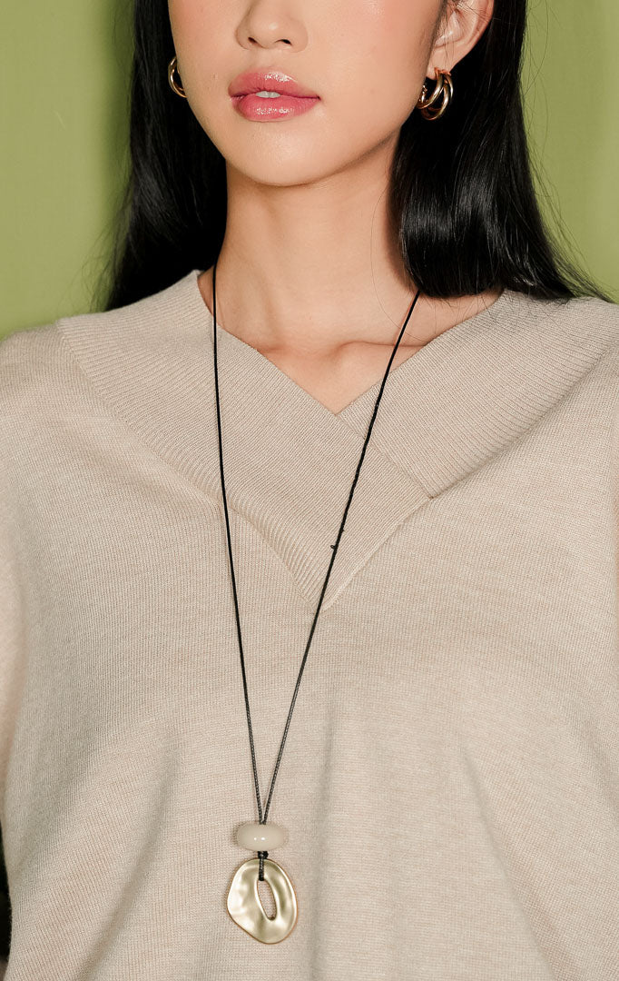 Sweater rajut wanita Venna Sweater lengan panjang warna beige polos, menampilkan detail kerah V-neck menyilang di bagian dada dengan aksen rajutan rib lebar yang khas, serta ujung lengan dan bawah beraksen rib.