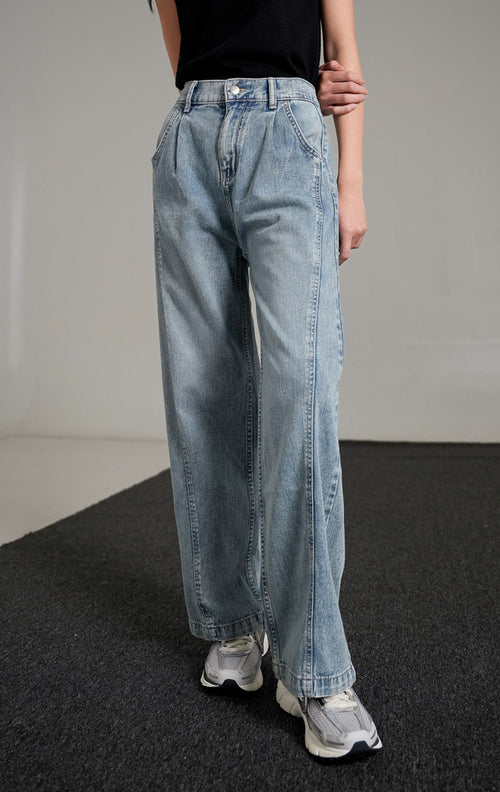Vespera Pants Light Denim, celana jeans biru muda potongan lurus (straight leg) dengan detail lipatan depan, dipadukan dengan tank top hitam dan sneakers.