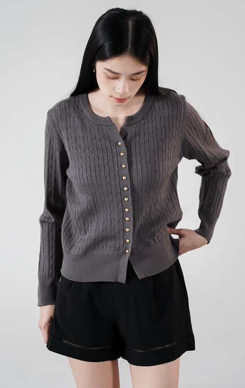 Vinnie Cardigan warna dark grey, kardigan rajut kabel (cable knit) lengan panjang dengan deretan kancing elegan, dipadukan dengan celana pendek hitam1