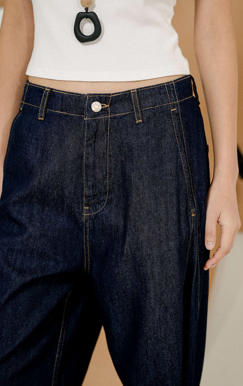 Model berdiri dengan tangan di saku mengenakan Vireya Baggy Denim Pants Dark Denim, produk celana jeans wanita model loose baggy warna biru tua dengan detail jahitan kontras.