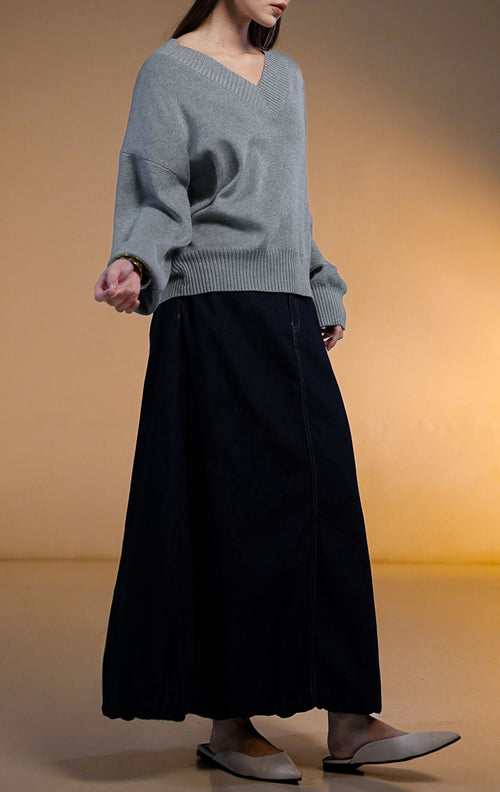 Model wanita memakai Walker Outer Sweater, atasan rajut V-neck warna beige krem dengan celana panjang coklat tua.