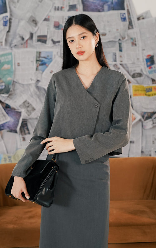 Model mengenakan Windlow Outer Dark Grey, luaran wanita potongan pendek (crop) warna abu-abu tua, bahan polyester kokoh yang membentuk struktur, dan kancing depan.