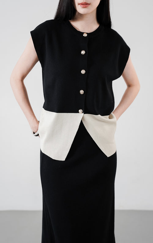 Xandria Set warna hitam, setelan rajut yang terdiri dari atasan tanpa lengan berkancing depan dengan aksen hem warna krem, serta rok panjang hitam senada.

