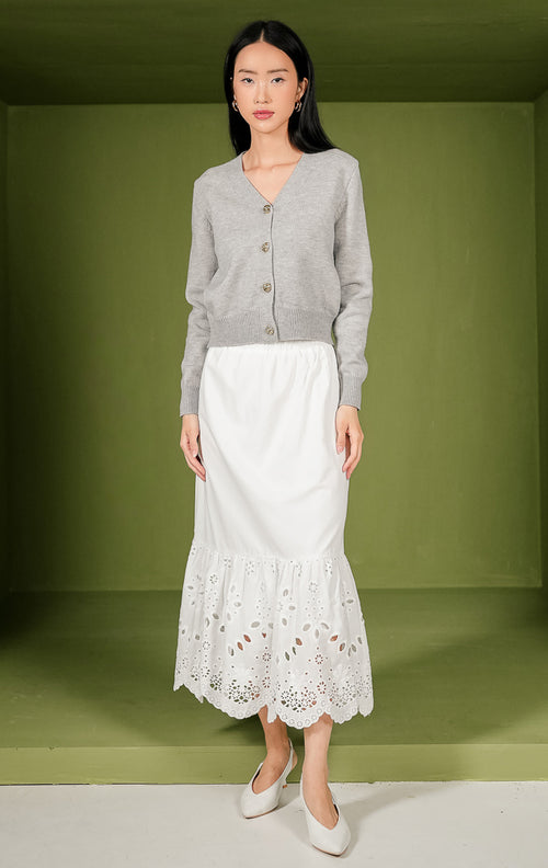 Kardigan rajut wanita Yonna Cardigan model crop warna abu-abu polos lengan panjang, dilengkapi kerah V-neck, detail rib pada ujung lengan dan bagian bawah, serta empat kancing metal berwarna emas di bagian tengah depan.


