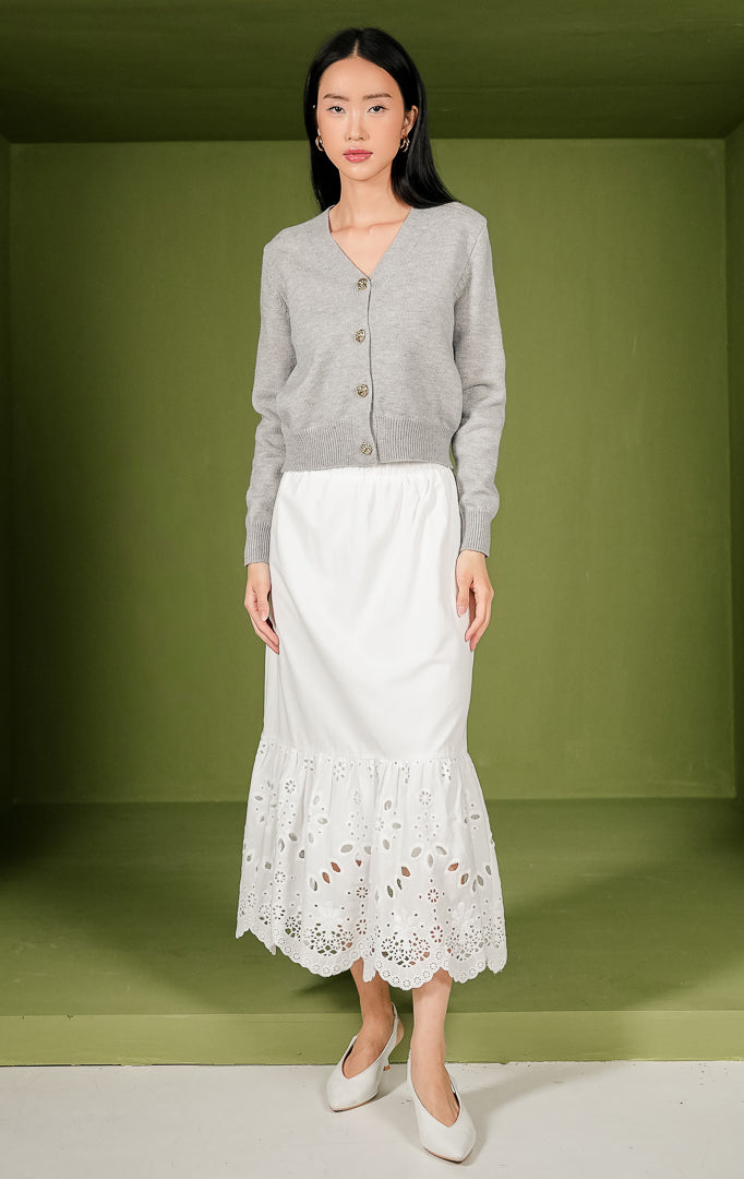 Kardigan rajut wanita Yonna Cardigan model crop warna abu-abu polos lengan panjang, dilengkapi kerah V-neck, detail rib pada ujung lengan dan bagian bawah, serta empat kancing metal berwarna emas di bagian tengah depan.

