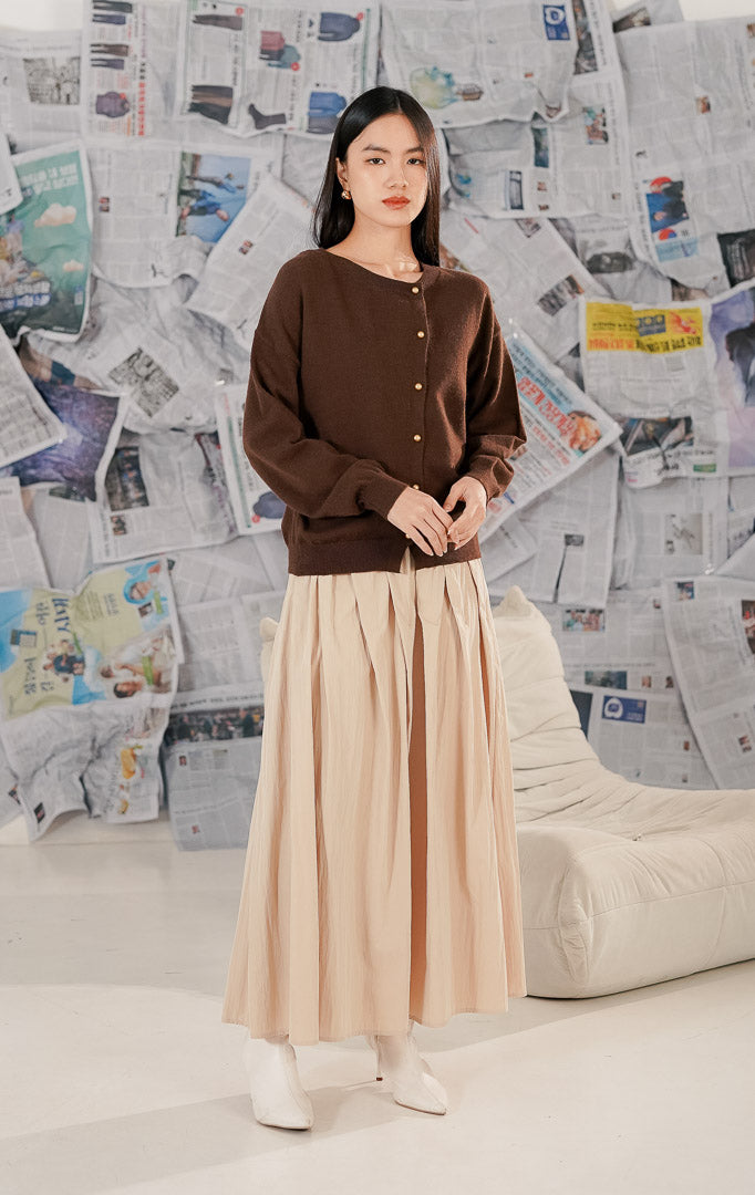 Model mengenakan Yurri Cardigan Brown, cardigan rajut wanita warna cokelat (earth tone) dengan detail kancing emas depan yang elegan dan bahan melar yang nyaman.